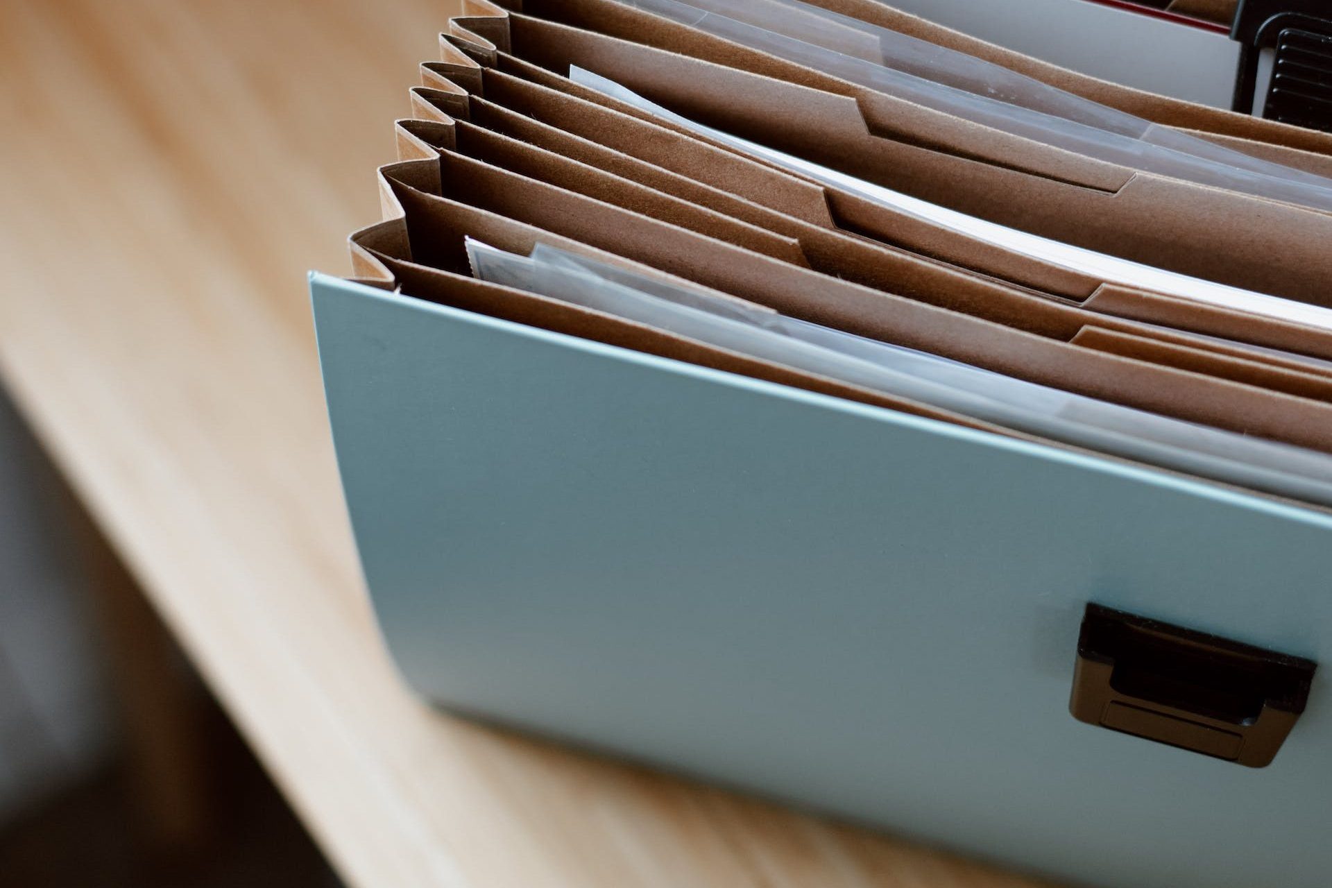 From above of opened modern briefcase with prepared papers placed on timber table in soft focus